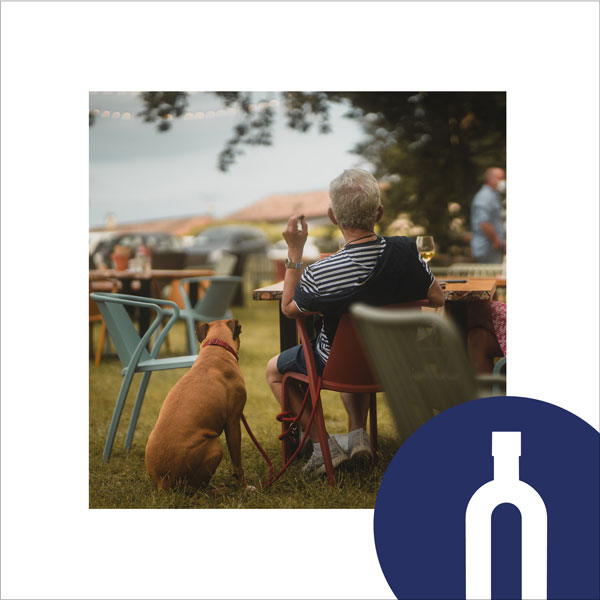 Guinguette Fronton - restaurant Un été à la campagne Homme assis avec son chien picto bouteille de vin bleu